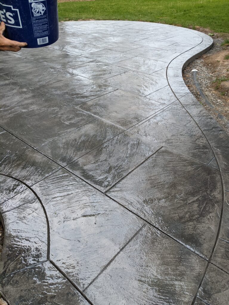 Wet-look sealed stamped concrete patio with tile pattern and curved edge