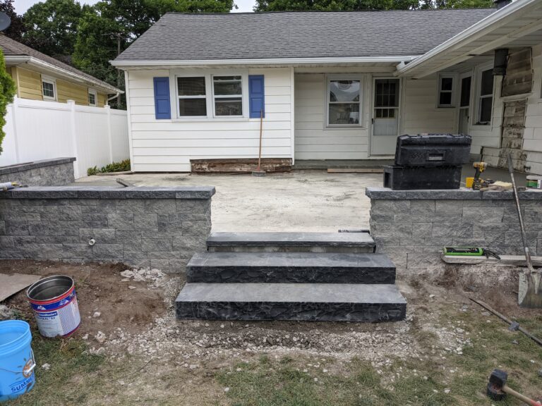 Stone veneer retaining wall and concrete steps with natural stone patio
