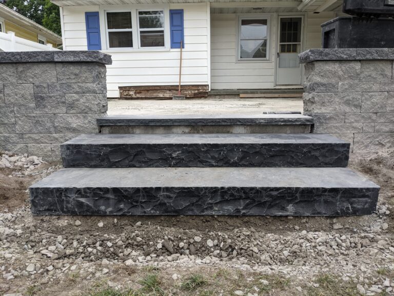 Dark charcoal natural stone veneer steps leading to raised patio