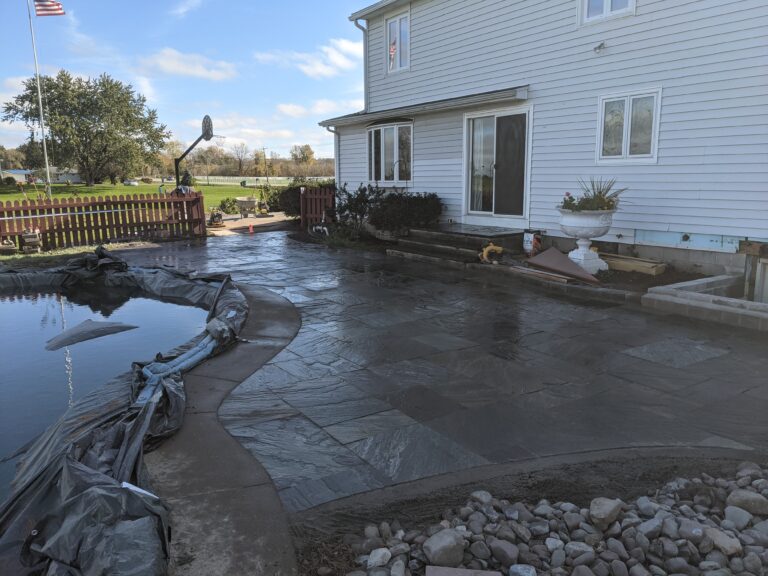 Dark flagstone patio with curved borders around decorative pond