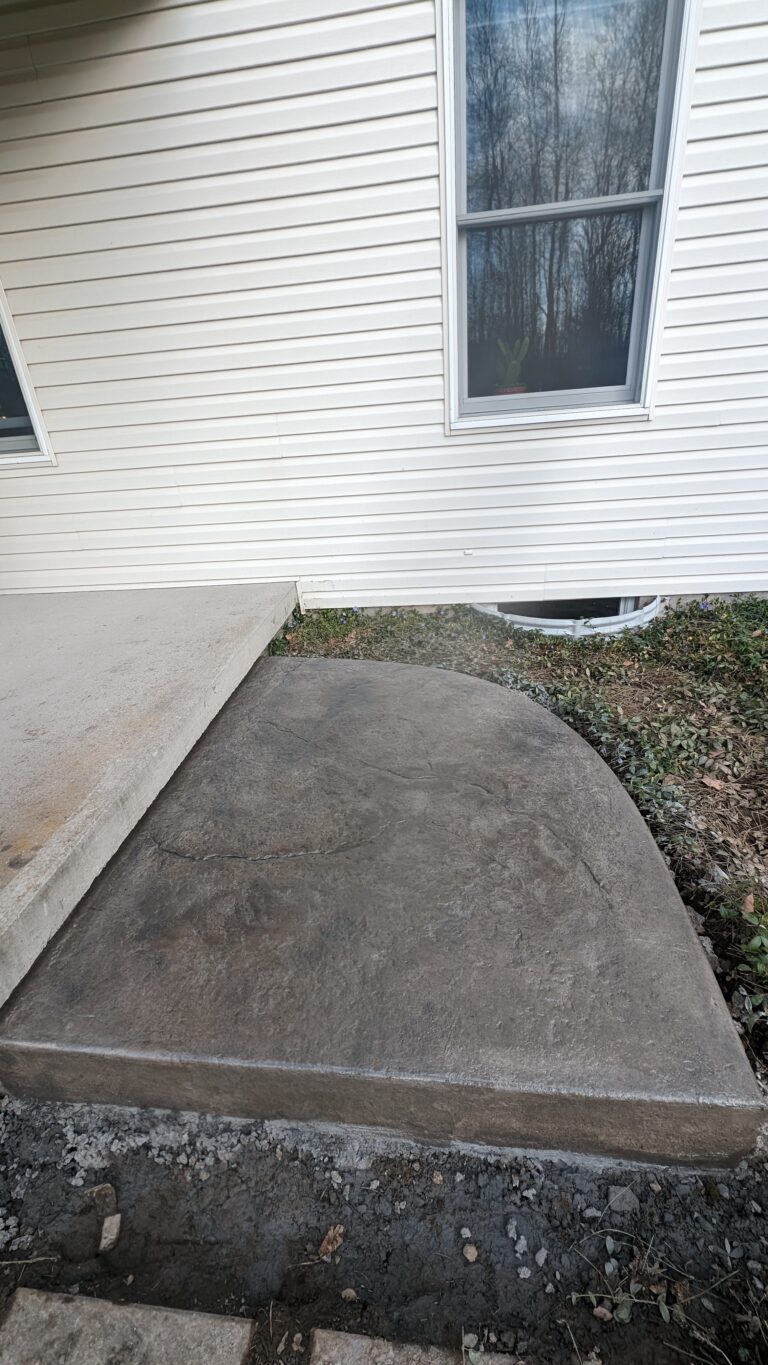 Stamped concrete step landing with stone texture beside foundation