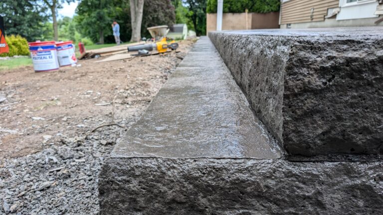 Corner detail of stamped concrete steps with stone veneer risers
