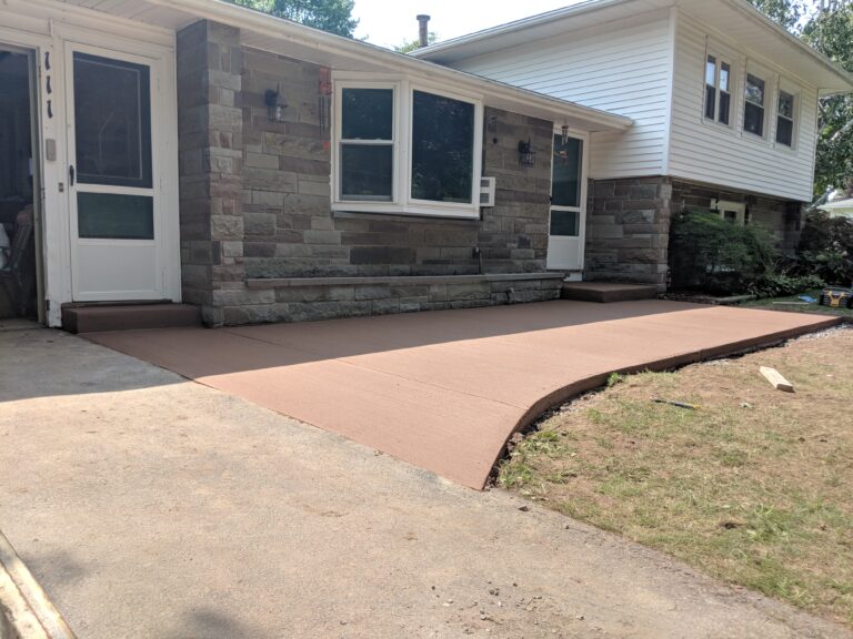 Colored concrete front patio with natural stone facade
