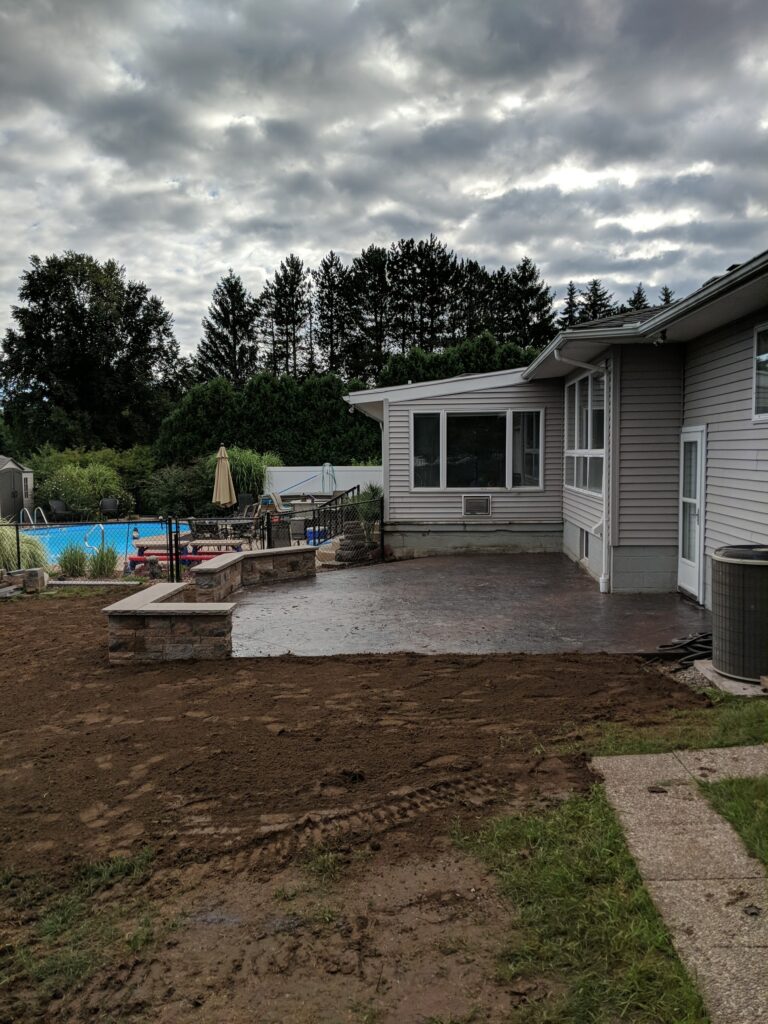 Stamped concrete patio with stone seat wall near pool