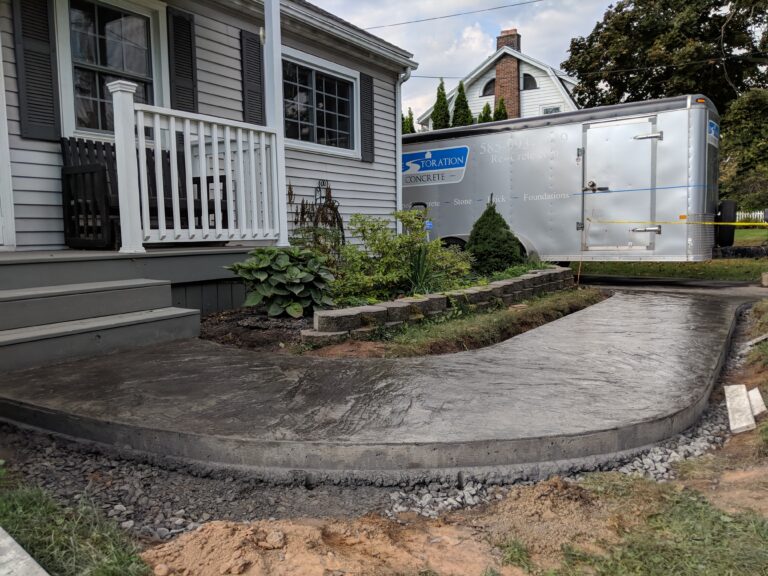 Stamped concrete front patio with stone border wall