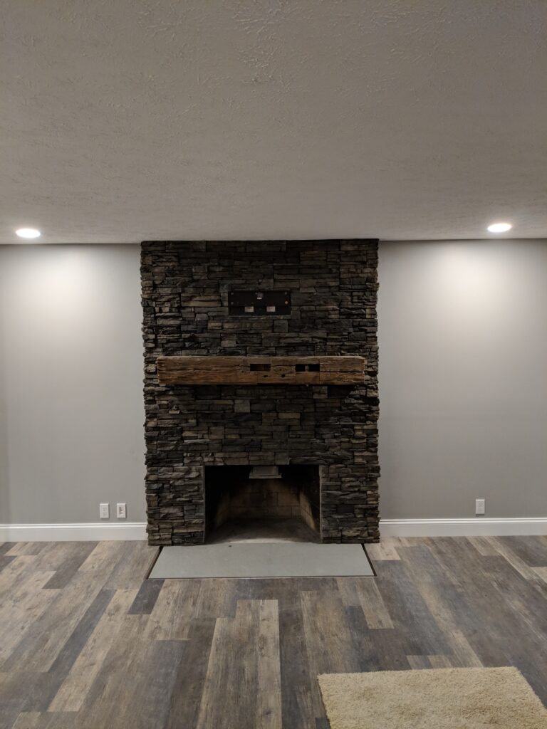 Stacked stone fireplace with reclaimed wood mantel - full room view