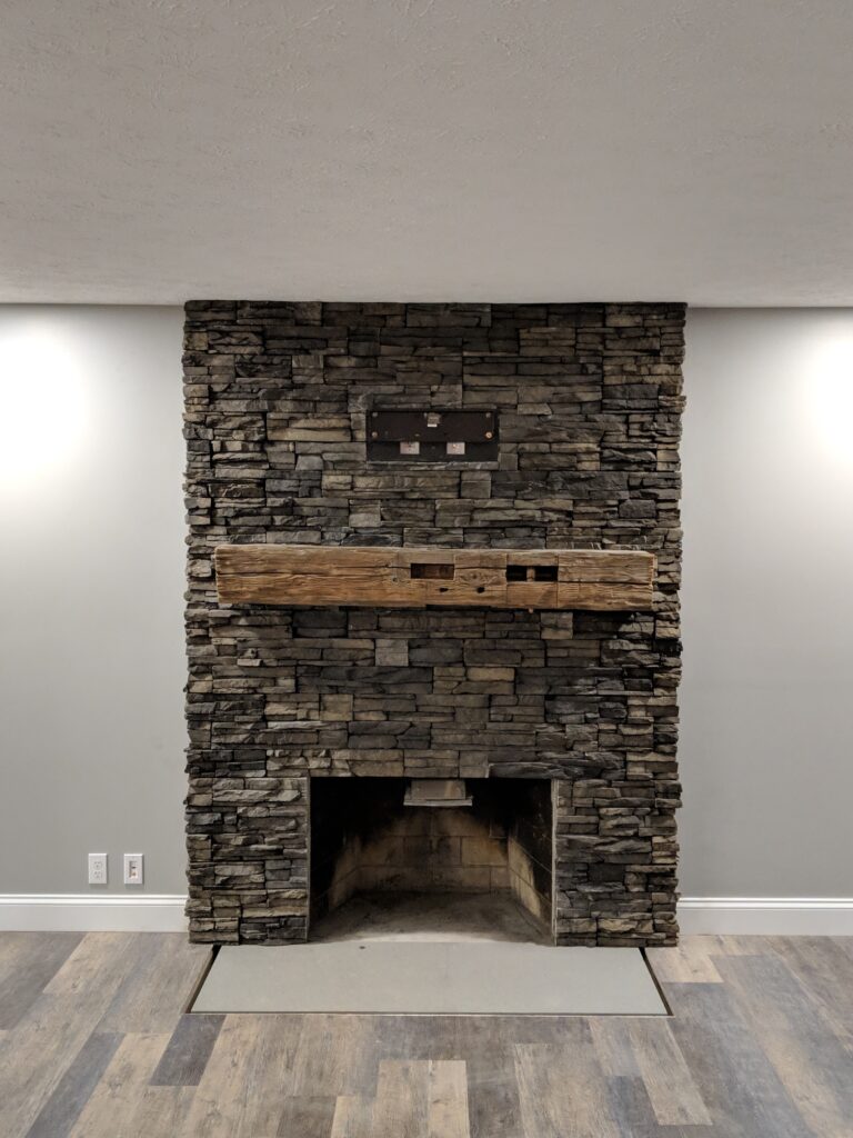 Stacked stone fireplace with reclaimed wood mantel - close view