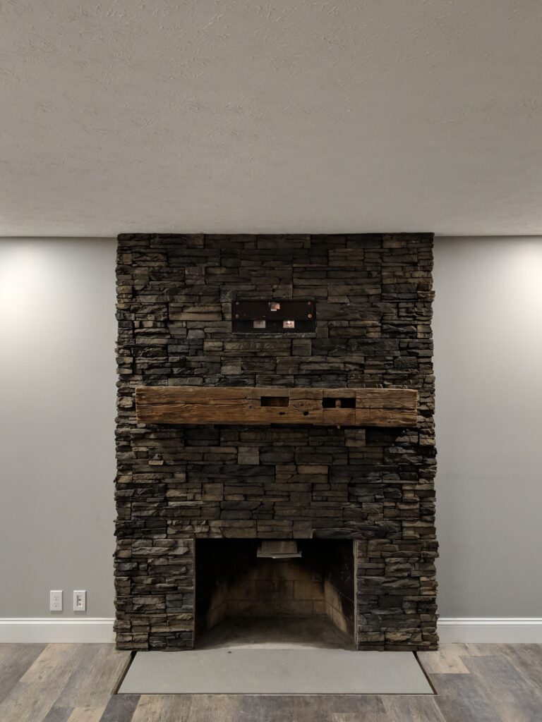 Stacked stone fireplace with reclaimed wood mantel - detail view