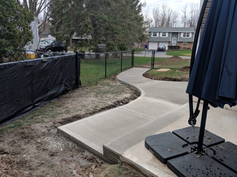 Curved concrete walkway extending to backyard