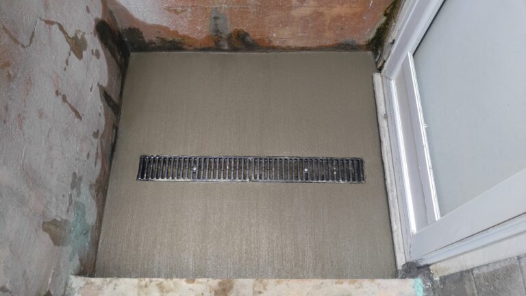 Linear slot drain installed in a concrete stairwell enclosure near a basement door – Rochester NY drainage contractor