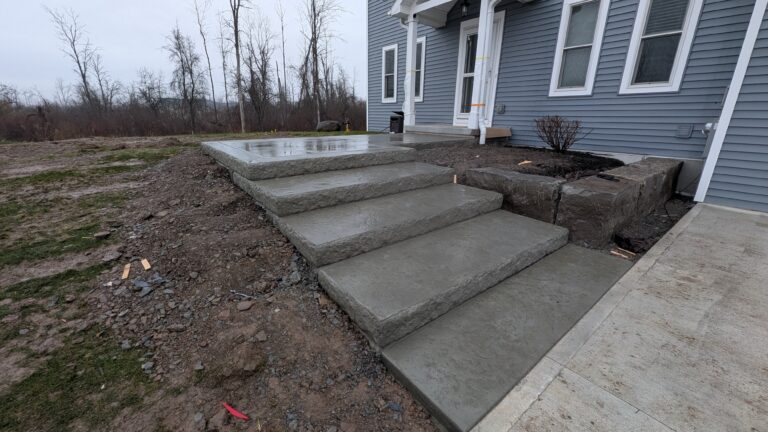 Wide natural stone slab steps and concrete landing leading to front door of new construction home, Rochester NY area