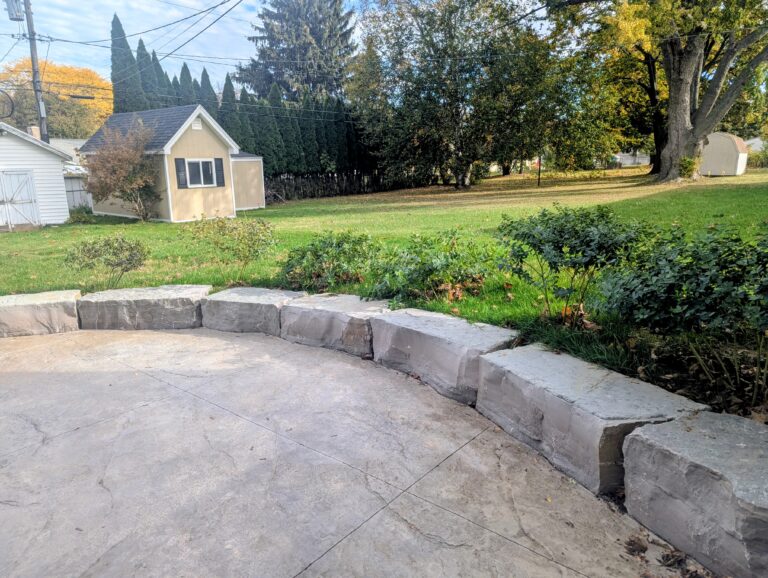 Stamped concrete patio with curved natural boulder seat wall in backyard, Greece NY