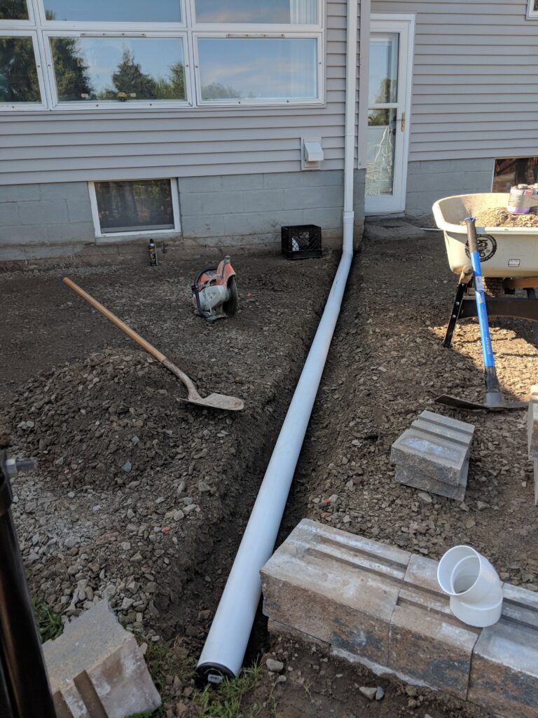 PVC drainage pipe laid along a residential foundation for a French drain installation – Rochester NY