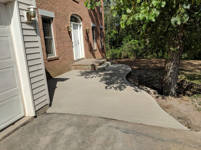 Broomed concrete driveway apron and side walkway at a brick home in the Rochester NY area