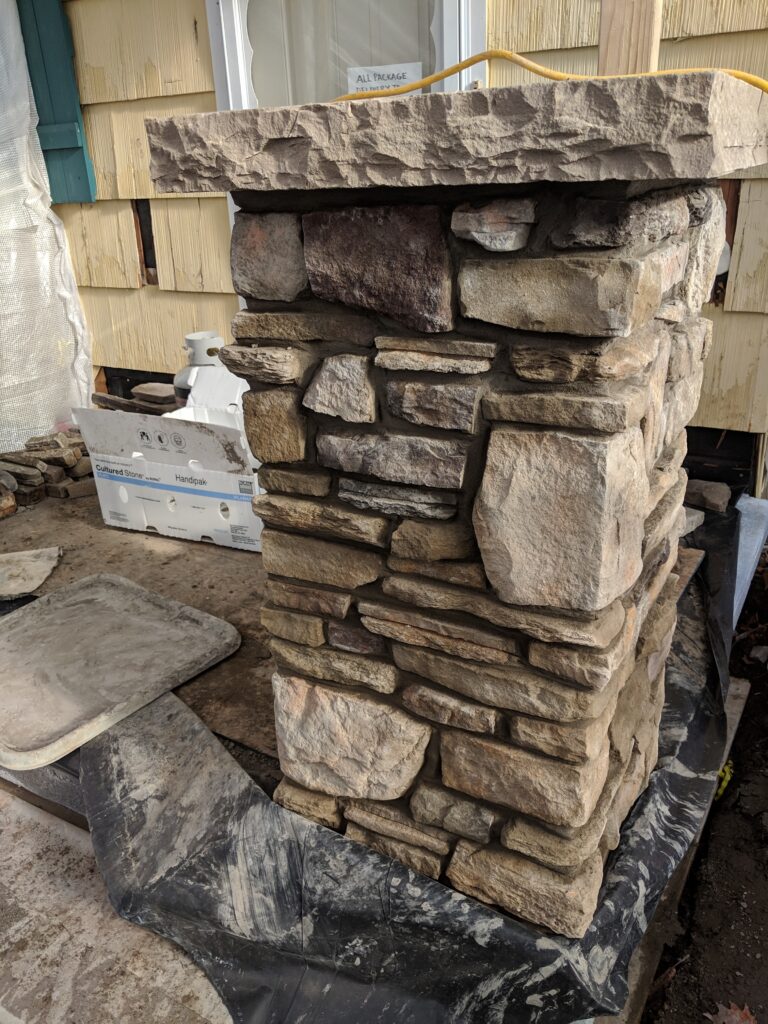 Close-up of natural fieldstone veneer column under construction with flat capstone, Rochester NY