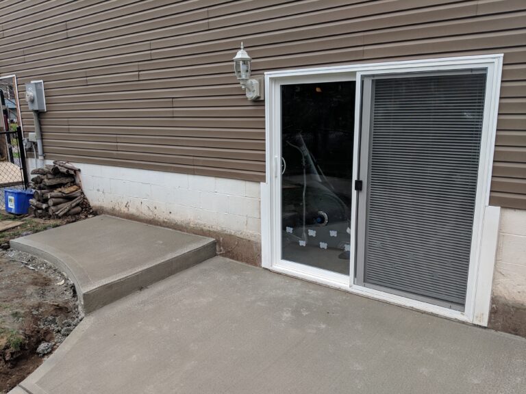 Broomed concrete back entry landing and step leading to sliding glass doors at a Rochester NY home