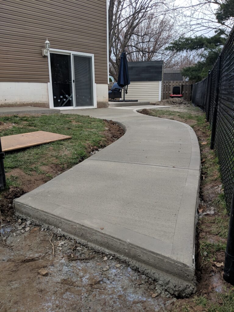 Freshly poured broomed concrete curved rear walkway leading to sliding back door entry, Rochester NY
