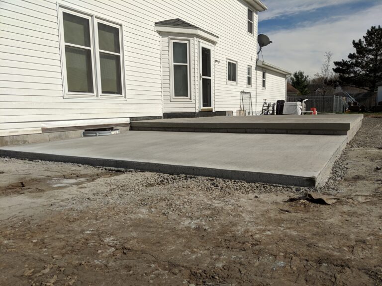 Freshly poured broomed concrete rear patio with expansion joints at a Rochester NY home, still curing
