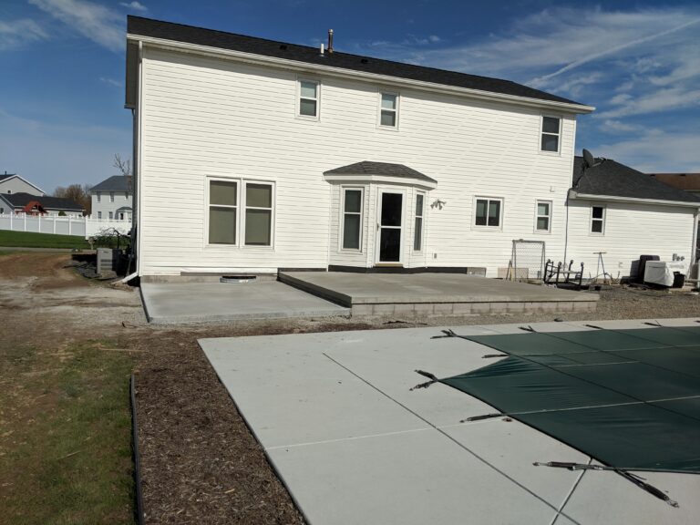Broomed concrete rear patio with steps next to a covered inground pool at a Rochester NY home