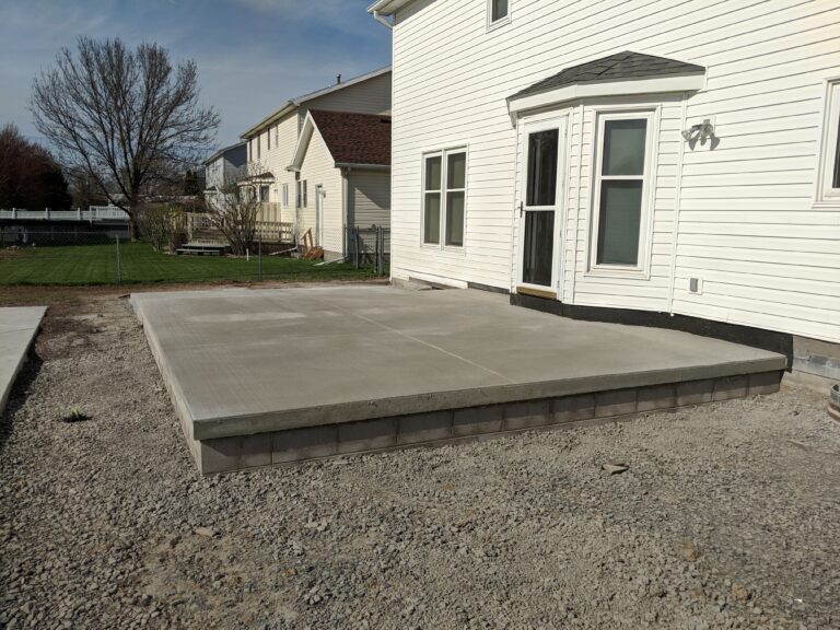 Broomed concrete backyard patio with concrete block border edging at a Rochester NY residential home