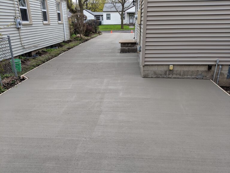 Wide freshly poured broomed concrete driveway between two residential homes in Rochester, NY