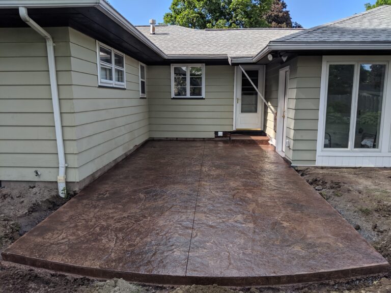 Large brown slate-texture stamped concrete patio installed at back of ranch home – Rochester NY