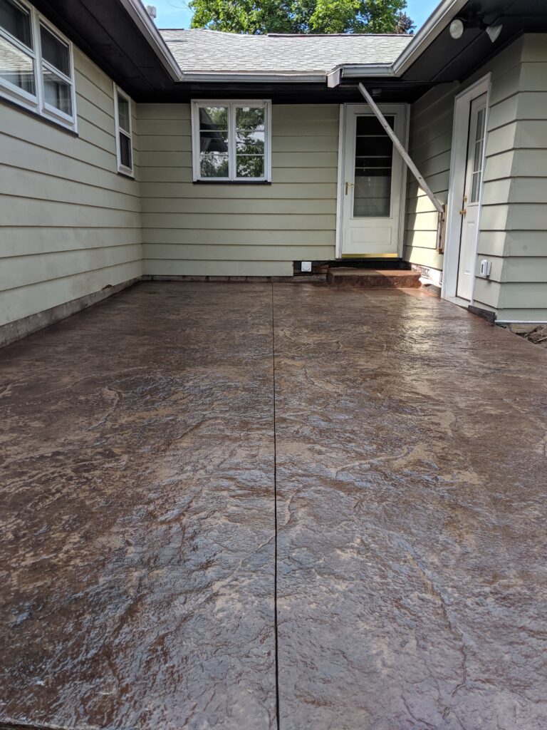 Brown stamped concrete rear patio with entry steps and back door access – Rochester NY