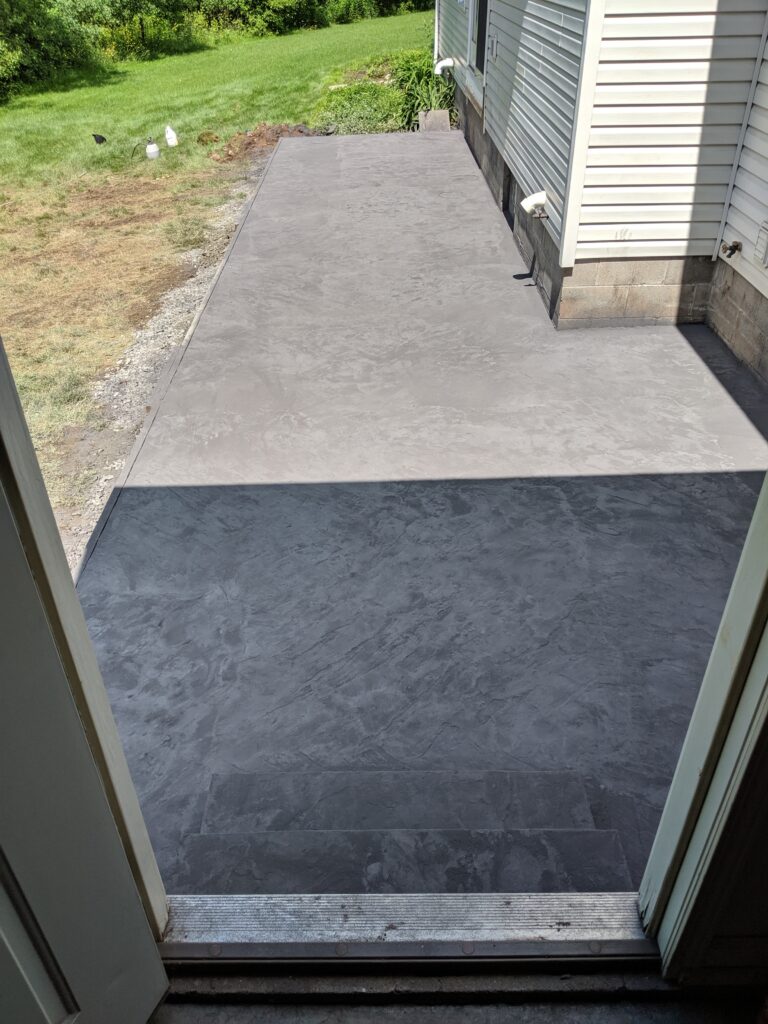 Smooth concrete walkway and slate-pattern patio alongside a Rochester NY home, freshly finished by Re-Crete