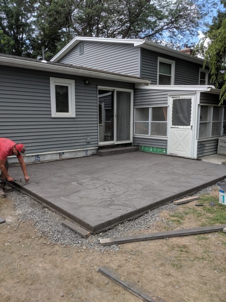 Wide view of flagstone stamped concrete patio freshly installed at two-story home – Rochester NY