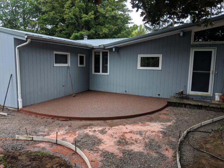 Exposed aggregate patio freshly poured at a Rochester NY home with forms still in place and gravel base visible