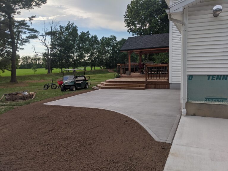 Large curved broomed concrete patio connecting to a wood deck with steps at a Rochester NY home