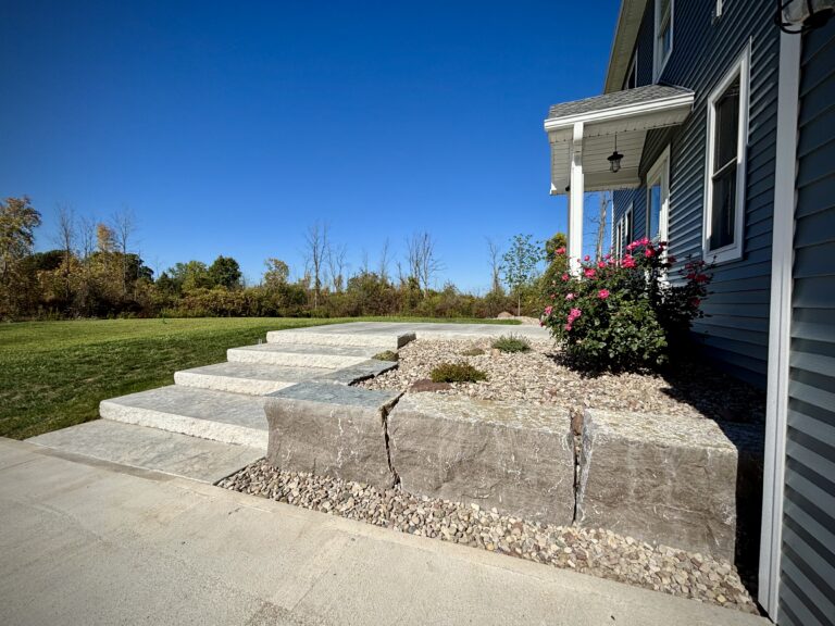 Side profile of natural stone slab steps cantilevered over boulder retaining wall with gravel landscaping