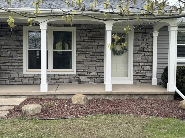 Close-up of grey ledgestone veneer between white porch columns showing stone pattern detail