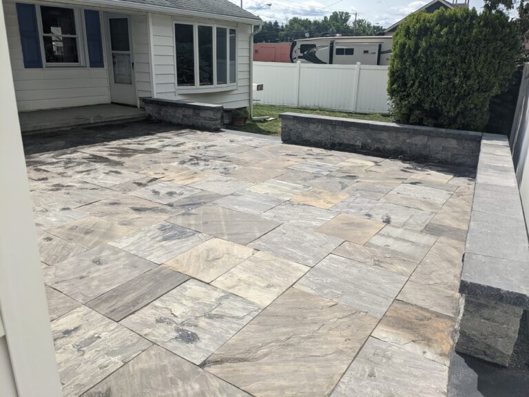Large natural stone tile patio with low boulder seat wall in backyard, Victor NY