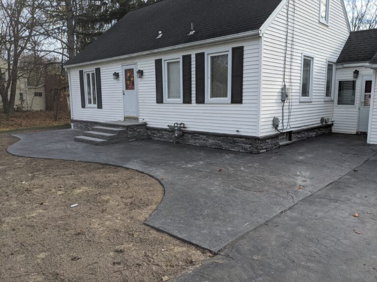 Ledgestone stone veneer on home foundation exterior skirt alongside new concrete driveway and steps, Rochester NY