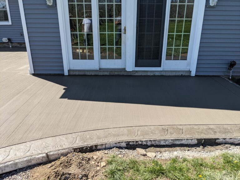 Close-up of fresh broomed concrete patio with stamped concrete curved border near French doors in Penfield NY