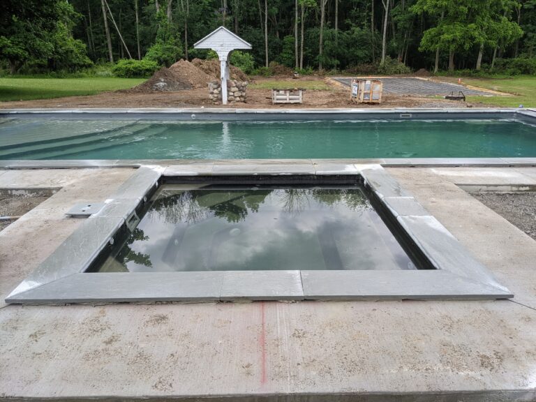 Newly poured concrete pool deck surround with wood forms in place around a covered in-ground pool in Rochester NY
