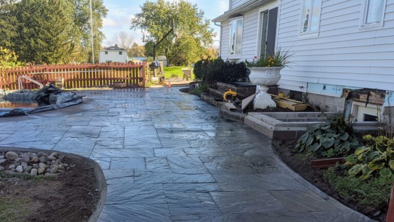 Natural stone tile patio wrapping around in-ground pool with curved border edge, Monroe County NY