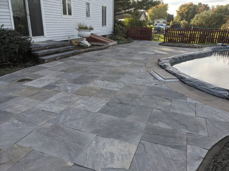 Finished natural stone tile patio with covered in-ground pool and stone steps to back door, Rochester NY