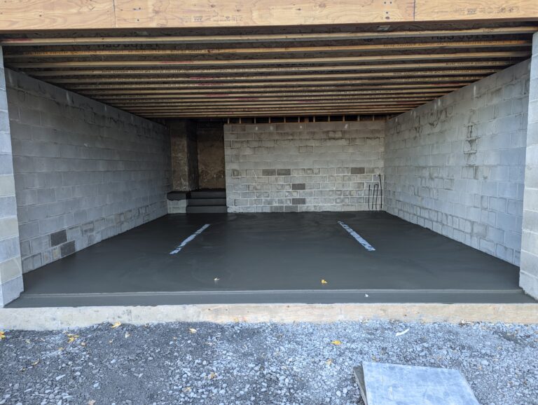 Freshly poured smooth concrete basement floor over radiant heat system inside cinder block foundation in Rochester NY