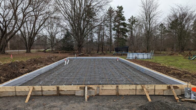 Steel rebar grid fully laid in wooden foundation slab formwork ready for concrete pour – Rochester NY