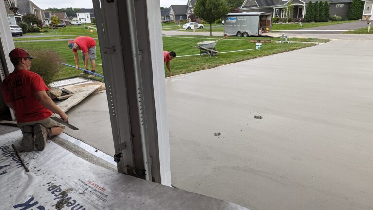 Re-Crete crew members hand-finishing a freshly poured concrete driveway at a Rochester NY residential job site