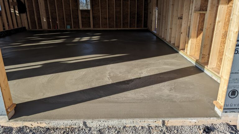 Freshly poured concrete garage floor in new construction garage with OSB sheathing in Rochester NY