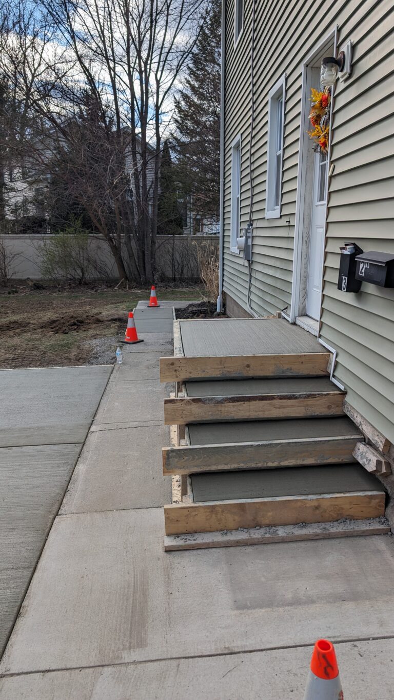 New broomed concrete front steps with forms still in place and safety cones at a Rochester NY home