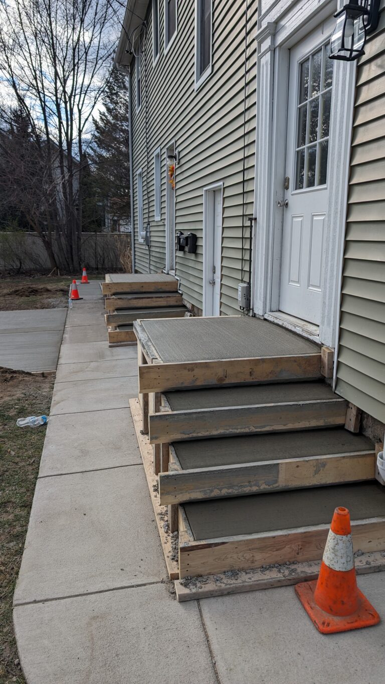 Close-up of new broomed concrete front entry steps with wooden forms still in place at a Rochester NY home