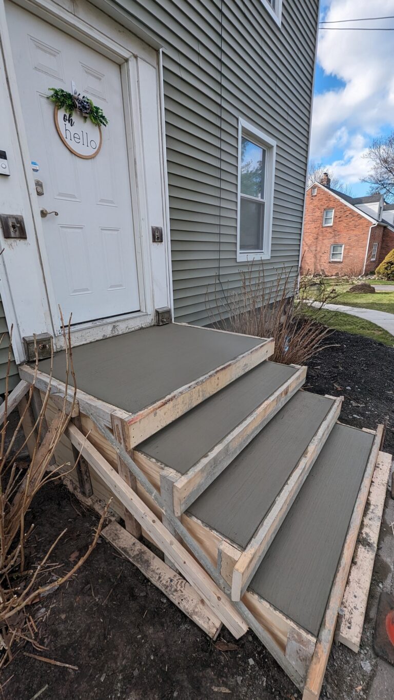 Completed broomed concrete front entry steps with wreath on door at a Rochester NY home after form removal