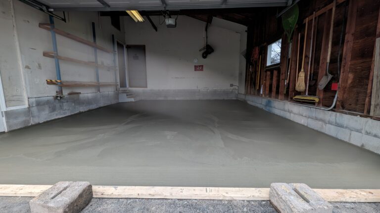Low-angle view of freshly poured smooth concrete garage floor from entrance to back wall in Rochester NY