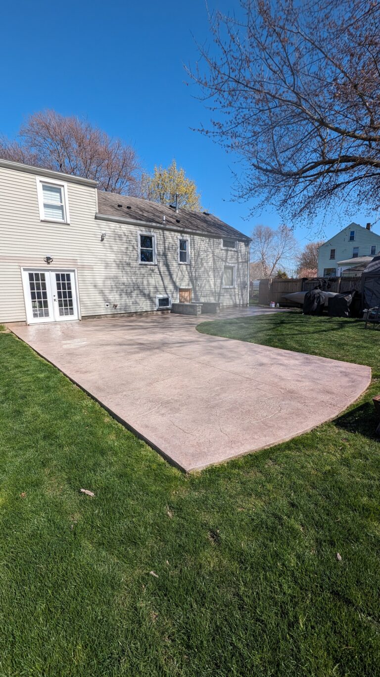 Large stamped concrete backyard patio with pink-tan flagstone texture and curved edge – Rochester NY