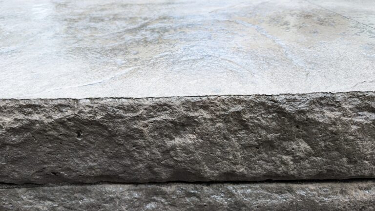 Close-up of stamped concrete step tread surface and chiseled stone-face riser edge – Rochester NY