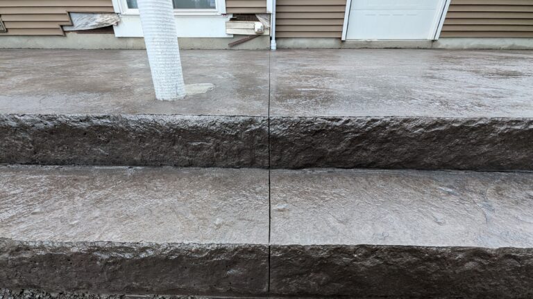 Top-down view of freshly poured stamped concrete steps with stone-face risers and adjacent patio – Rochester NY